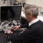 LaFT-Leiter Jens P. Wulfsberg demonstriert an einer Vorschubeinheit für Mini-2D-Werkzeugmaschinen, wie Armstütze aus dem 3D-Drucker den Monteur bei der Arbeit unterstützen. Exoskelette sollen die Arbeitssicherheit erhöhen.