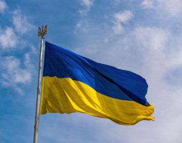 Ukrainian national official flag on flagpole waving in the wind on picturesque blue sky background