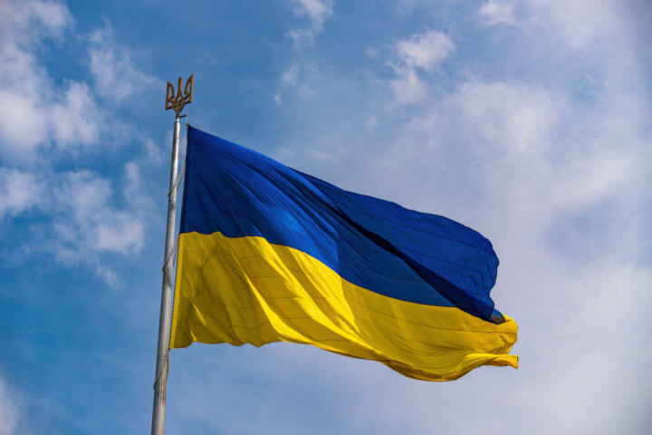 Ukrainian national official flag on flagpole waving in the wind on picturesque blue sky background
