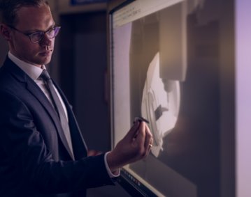 Marcel Wichmann hält ein reales Hüftimplantat vor seinen Digitalen Zwilling