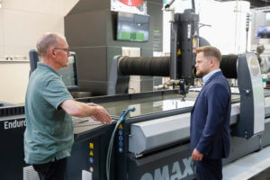 The moving head of the Omax OptiMAX 60X automatically compensates for the cone created by the waterjet, enabling high-precision waterjet cutting and the production of precise small angles in contours.