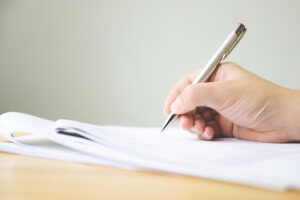 Hand of man signing signature filling in application form document